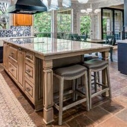 Elegant kitchen features stylish cabinet columns, a spacious island with seating, and abundant natural light from large windows, enhancing the inviting atmosphere and modern design.