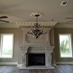 Elegant living room featuring intricate moulding and a grand chandelier, enhancing the overall sophistication and charm of the space. Bright natural light filters through large windows.