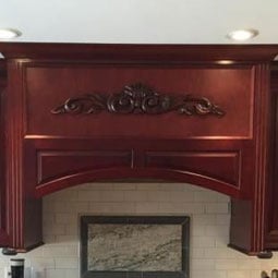 Elegant wooden kitchen cabinetry featuring intricate appliques and onlays, adding a touch of sophistication and craftsmanship to the modern kitchen design.
