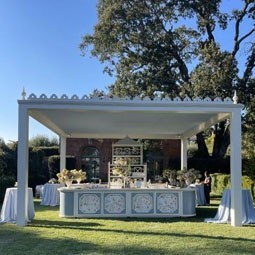Elegant outdoor setup featuring a spacious canopy, decorated tables, and lush greenery, perfect for hosting events amid a scenic backdrop. Ideal for wedding and party themes.