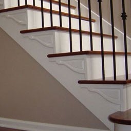 Elegant staircase featuring wooden steps and decorative white brackets, complemented by sleek black railing, enhancing a modern home interior. Perfect for DIY projects and renovations.