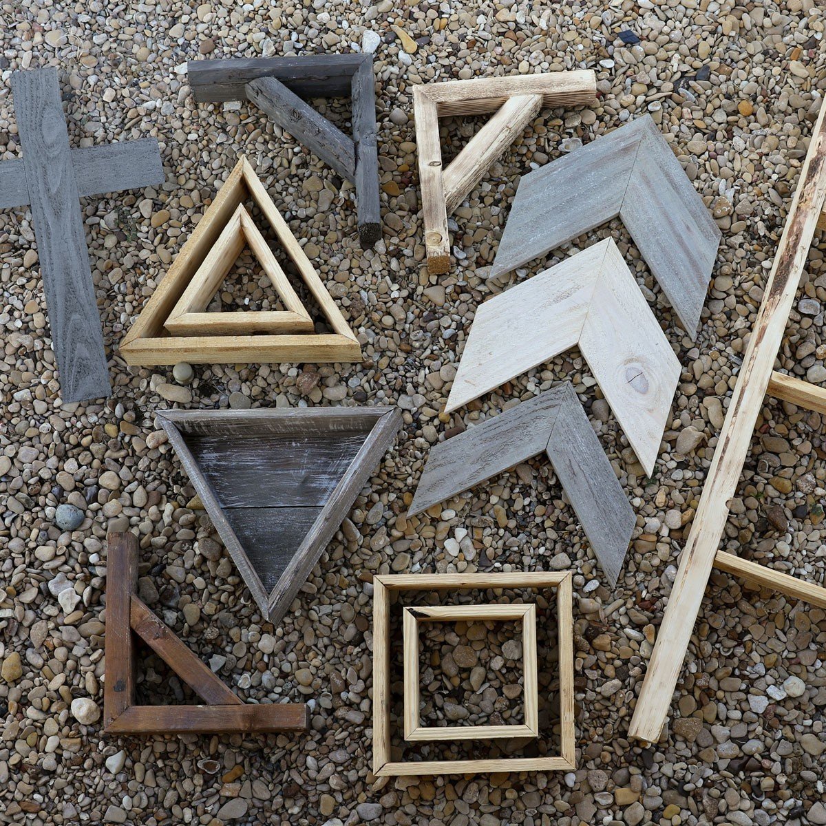 Natural textures of barnwood frames in various geometric shapes arranged on a pebbled surface, showcasing rustic decor elements ideal for enhancing home aesthetic.
