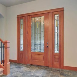 Stylish wooden double doors with decorative glass panels, enhancing the entrance of a modern home, surrounded by elegant stairway and stone flooring.