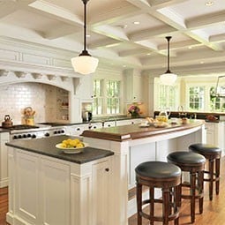 Bright kitchen featuring elegant coffered ceilings, large windows, and stylish seating. The design highlights the warm ambiance and sophisticated craftsmanship, perfect for modern living.
