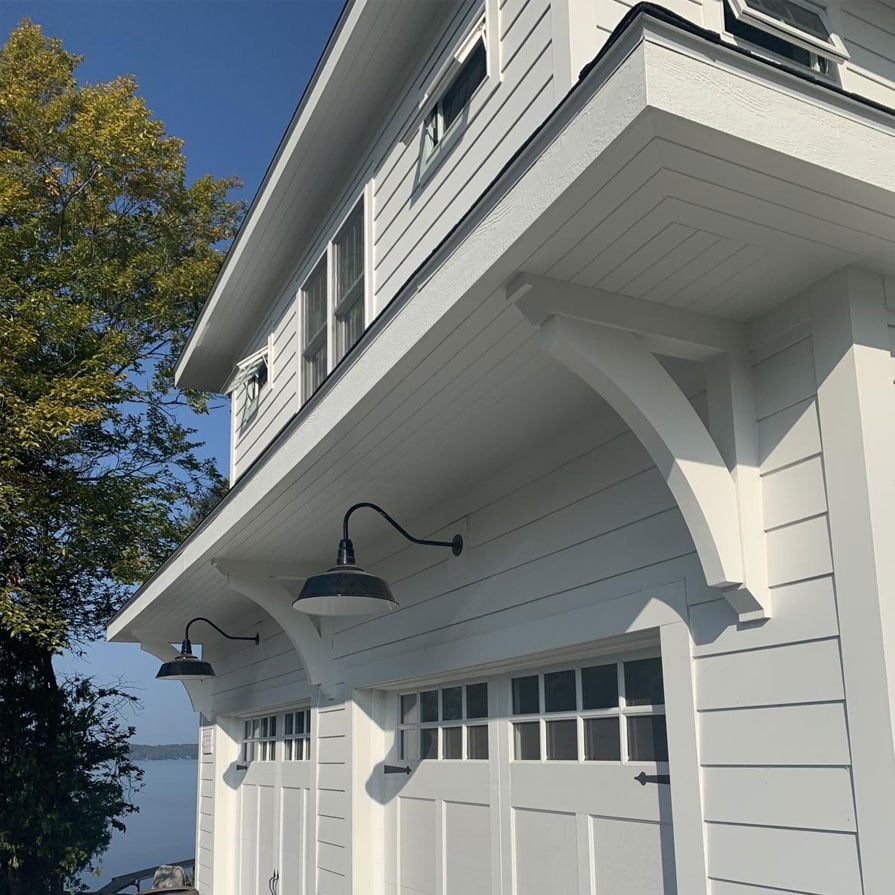 Elegant white corbels support a modern home's overhang, enhancing architectural beauty against a clear blue sky and lush greenery. Ideal for outdoor living aesthetics.