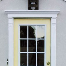 Stylish entryway featuring a bright yellow door framed by elegant white crossheads and headers, enhancing the home's curb appeal and inviting ambiance.