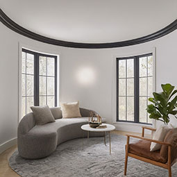 Stylish interior showcasing a curved sofa, round rug, and elegant window design, highlighting the seamless integration of flexible moulding in modern home decor.