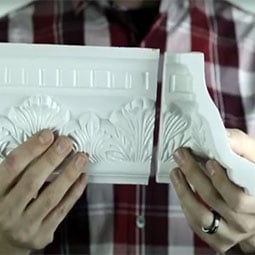 Person holding two pieces of miterless crown moulding, showcasing intricate detailing and seamless connection for easy installation in home decor projects. Ideal for stylish interior design.