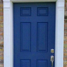 Elegant pilasters frame a deep blue door against textured brick, enhancing architectural appeal and adding sophistication to the entrance. Perfect for classic home designs.
