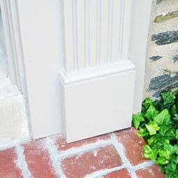Stylish plinth block enhancing architectural elegance at a doorway, blending classic design with modern aesthetics and complementing the surrounding brick and greenery.